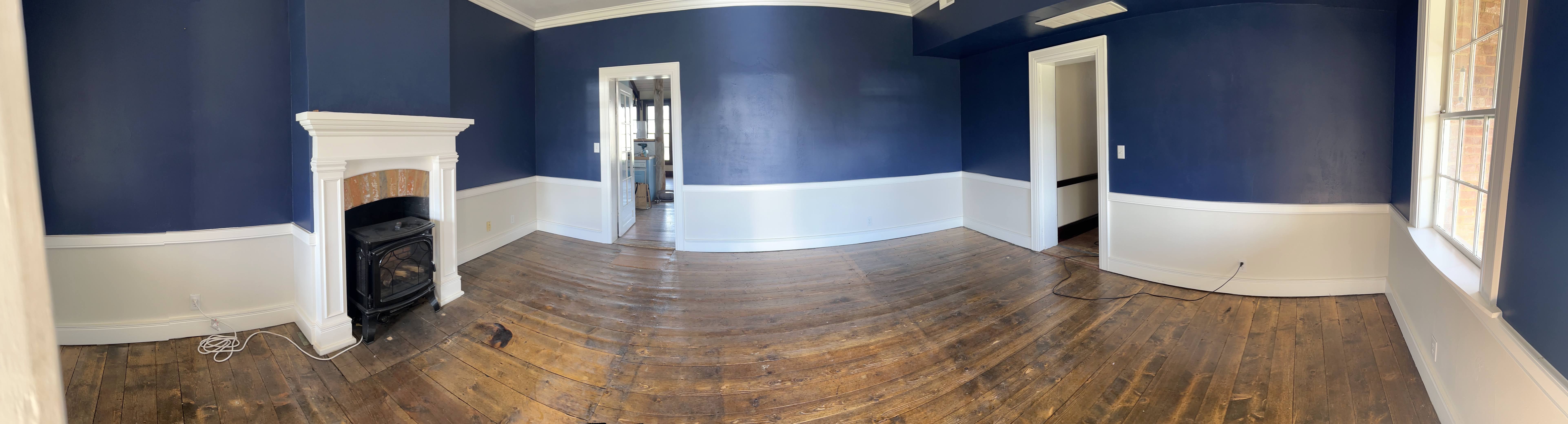 Angle of the living space showing the worn honey-toned flooring